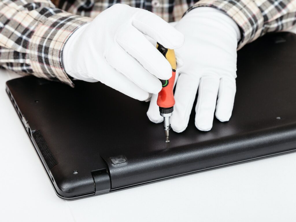 serviceman disassembles laptop with screwdriver